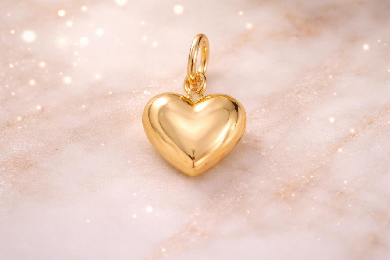 Polished gold heart charm pendant with glossy finish on soft neutral background